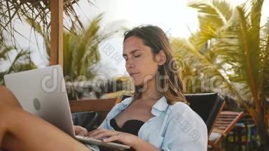 美丽<strong>专注</strong>的高加索工作狂商人在笔记本电脑移动办公室工作，在异国情调的海滩椅子度假。